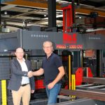 Productspecialist Wijnhold Pruis van Tuwi (links) schudt Arno van den Akker de hand bij de CNC-gestuurde boor-zaagstraat van de Portugese fabrikant M&G Steel Machines.