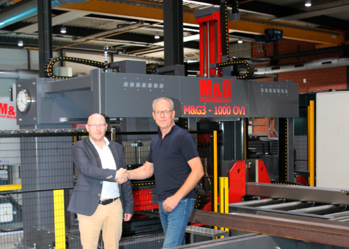 Productspecialist Wijnhold Pruis van Tuwi (links) schudt Arno van den Akker de hand bij de CNC-gestuurde boor-zaagstraat van de Portugese fabrikant M&G Steel Machines.